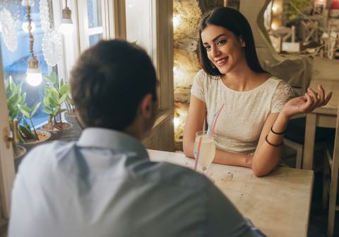 Portrait of smiling young woman talking to her boyfriend in a restaurant