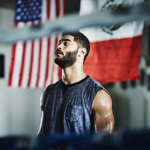 portrait of sweating male boxer listening to trainer during workout in boxing gym