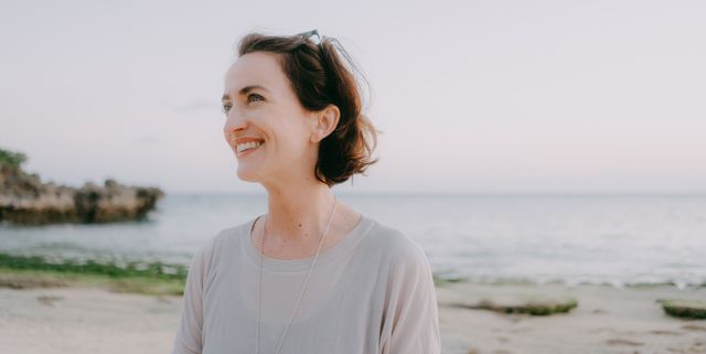 portrait of woman smiling on beach at sunset