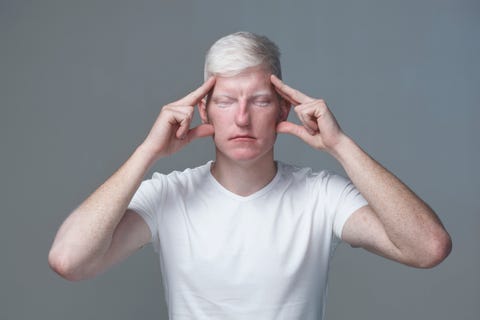 Portrait of young man focusing with closed eyes against gray background