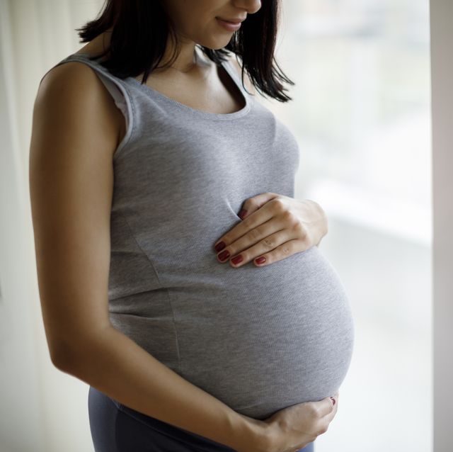 portrait of young pregnant woman standing by the window