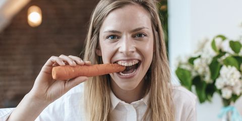 Portrait of young woman biting carrot
