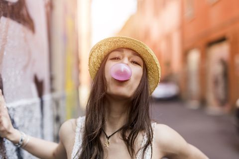 portrait of young woman blowing pink bubble gum