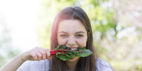 Portrait Of Young Woman Eating Leaf Vegetable