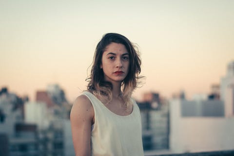 portrait of young woman standing against clear sky in city during sunset