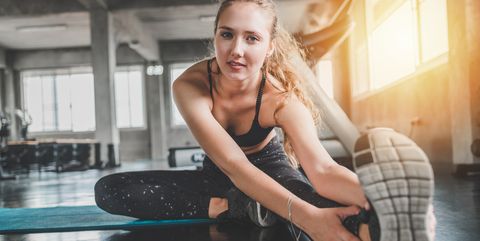 Portrait Of Young Woman Stretching Leg In Gym