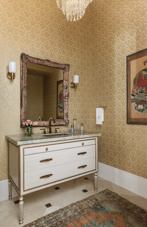 banheiro com papel de parede dourado e detalhes em latão