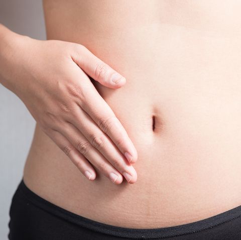 Pregnancy or diet concept, female hands protecting the stomach on white background.