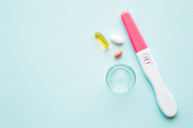 pregnancy test with two stripes on pastel blue background positive result receiving vitamins for mother and unborn baby health in pregnancy time empty place for medical text top view close up