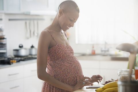Pregnant Black woman using digital tablet in kitchen