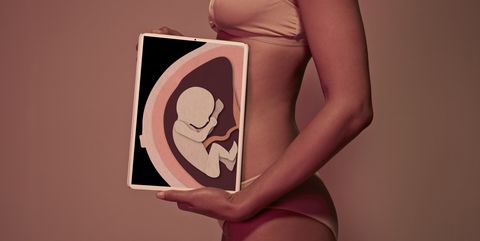 Pregnant young woman holding tablet in front of belly to display baby