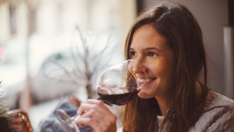 een gelukkige vrouw drinkt een glas rode wijn