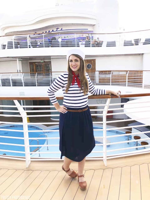 woman standing on deck of ship dressed as sailor with red scarf, sailor hat and striped shirt