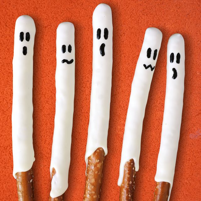 group of halloween ghost, candy dipped pretzel rods on black stone background