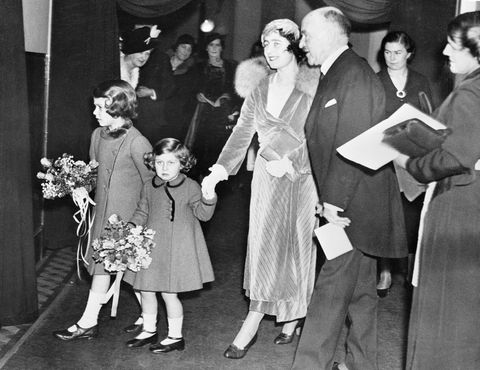 princess elizabeth and princess margaret, holding thier mother's hand, walks out of their performance of christmas carols holding flower bouquets