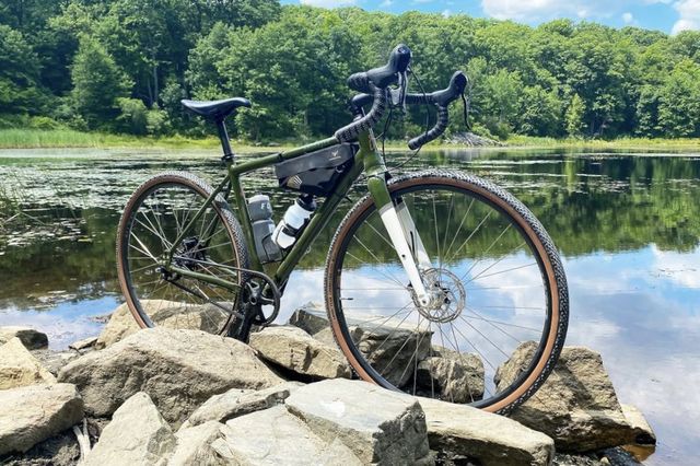 a bicycle parked on rocks by a body of water