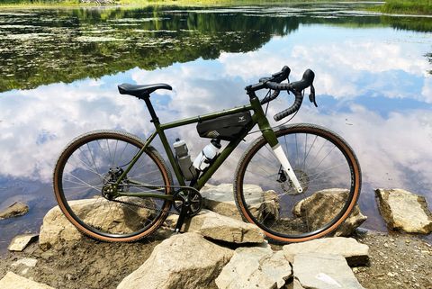 a priority apollo bike parked on some rocks overlooking a pond
