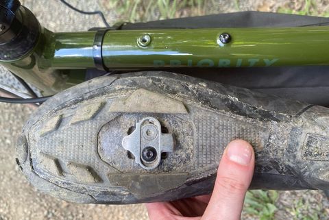 the underside of a bike shoe next to the middle bar of a priority apollo bike