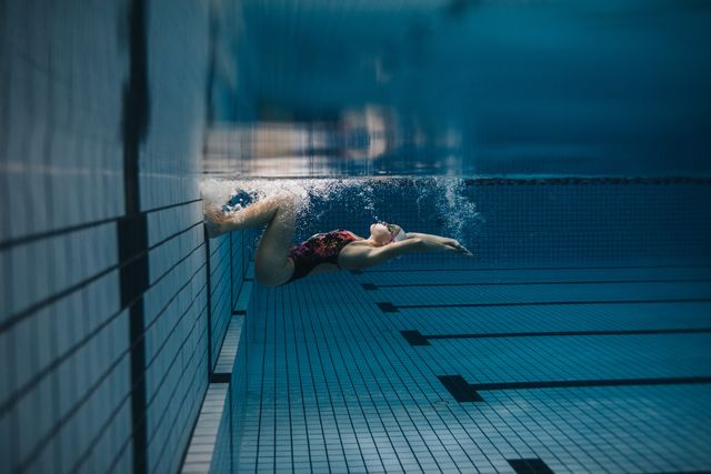 shot of fit young woman turning over underwater female swimmer in action inside swimming pool