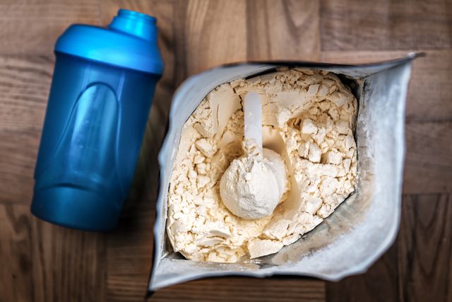 opened packaging of whey protein and blue shaker