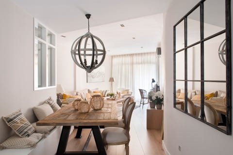 comedor abierto de estilo rústico e industrial con mesa de madera y espejo con cuarterones