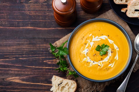 Pumpkin and carrot soup with cream and parsley Top view