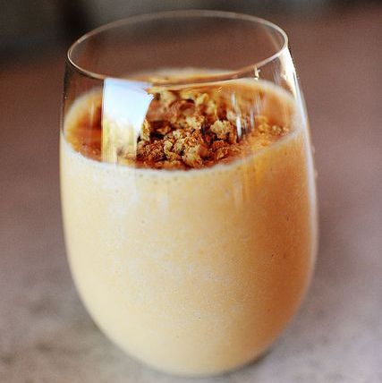 pumpkin smoothie with granola on top in glass cup