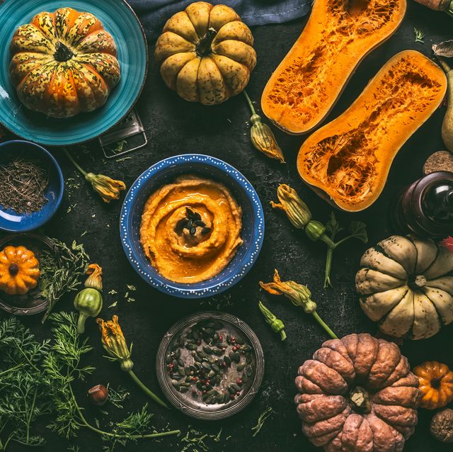 pumpkin hummus in blue bowl and various colorful autumn ingredients, top view