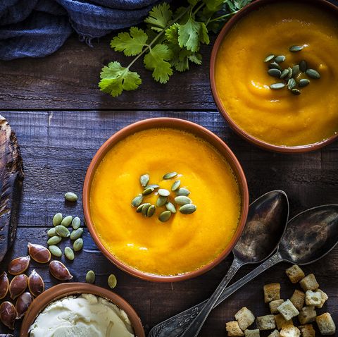 Pumpkin soup with ingredients on rustic wooden table
