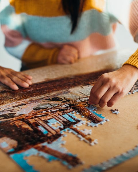 close up shot of the hands of a couple doing a jigsaw puzzle in their kitchen, shot from in front