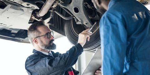 quality of service auto mechanic manager and mechanic investigated suspension system underbody of car together at auto repair center