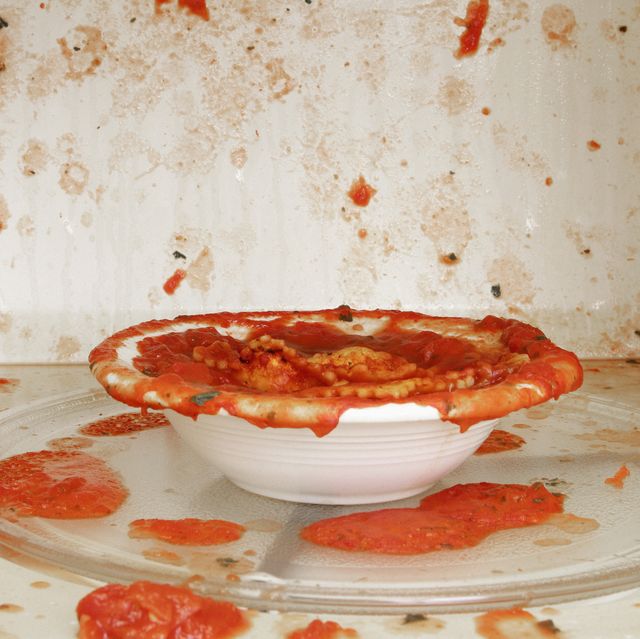 plato de salsa de tomate desperdigada manchando el interior de un microondas