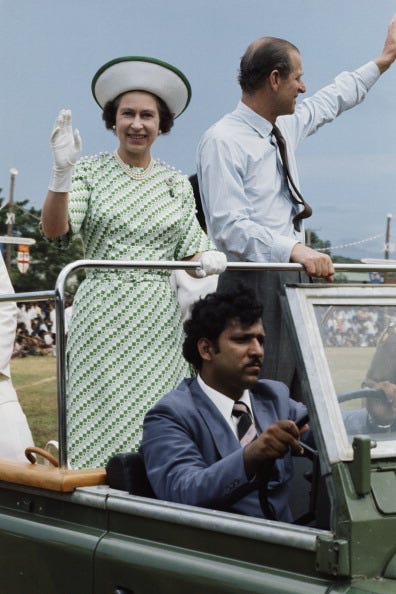 queen elizabeth and prince philip wave to the crowd while standing on the back of a vehicle in fiji