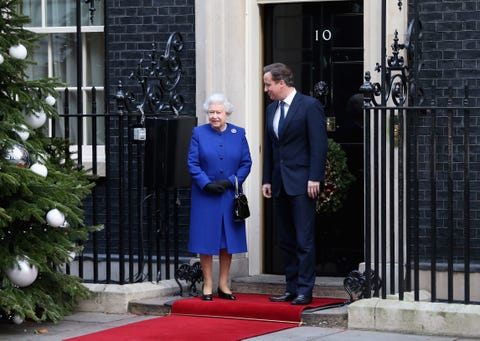 queen elizabeth ii attends the government's weekly cabinet meeting in a blue suit, with a decorated christmas tree and red carpet in front of the main entrance