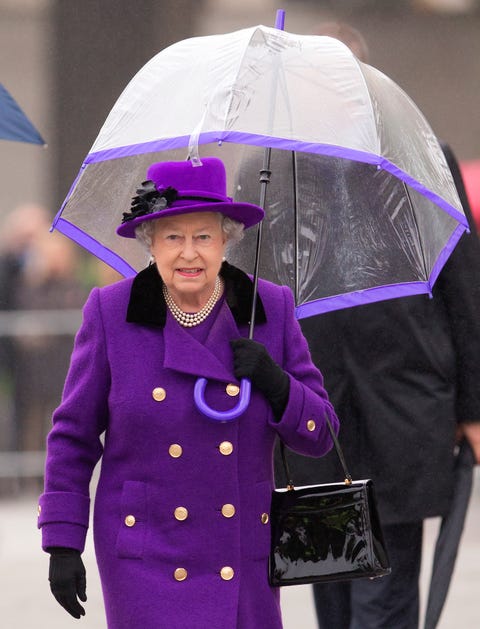 queen elizabeth ii walks in a purple coat and matching purple umbrella