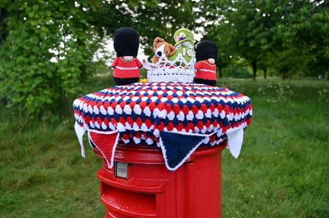 a knitted queen elizabeth ii with a corgi and accompanying guards is pictured above a post box in hangleton near hove, east sussex
