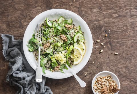 quinoa and greens veggies salad for a spring detox salad with quinoa, cucumbers, avocado, arugula, ginger, flax seeds and nuts on wooden background, top view mediterranean style food concept