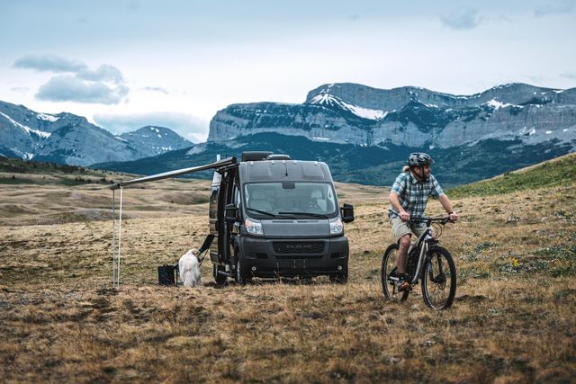 airstream rangeline parked in a field with mountains in the background and a mountain biker in the foreground