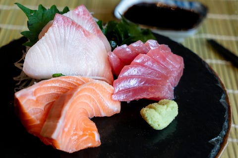 Raw fish Sashimi traditional Japanese food set includes Raw Salmon, Raw Tuna, Raw Yellow Tail (Hamachi) Sliced with sliced radish and vegetable