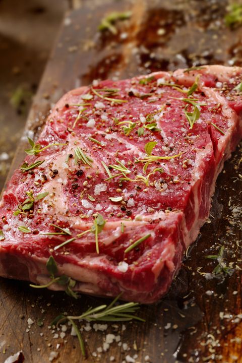 raw rib eye steak with fresh herbs