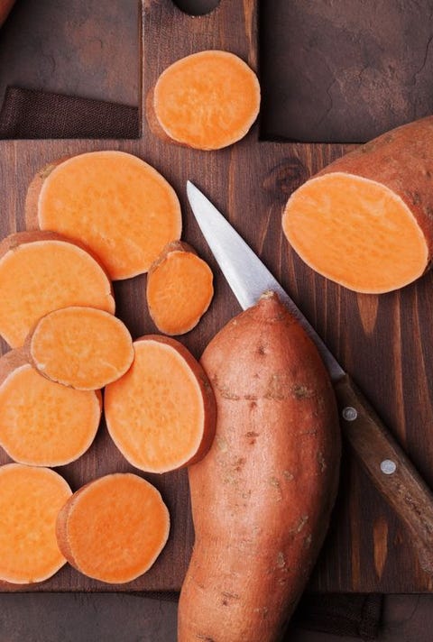 Rawsweet potatoes on wooden kitchen board top view. Organic food.