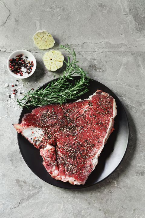 Raw t-bone steak with herbs and spices