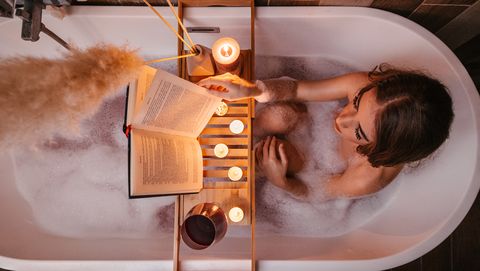 vrouw leest in een badkuip met kaarsjes aan