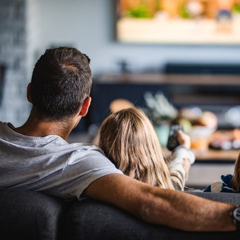 rear view of a family watching tv on sofa at home