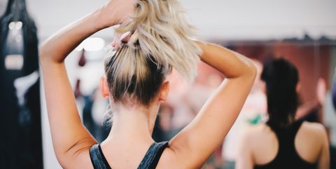 Rear view of blond woman tying ponytail at gym