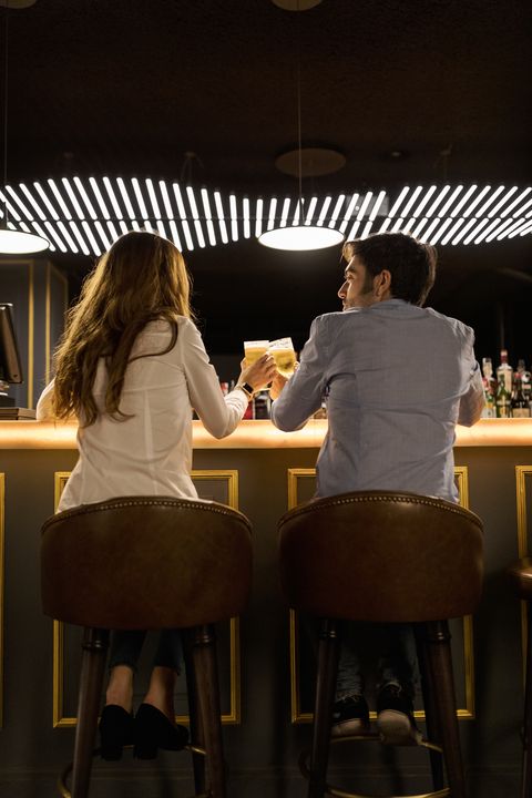 rear view of couple clinking beer glasses in a bar