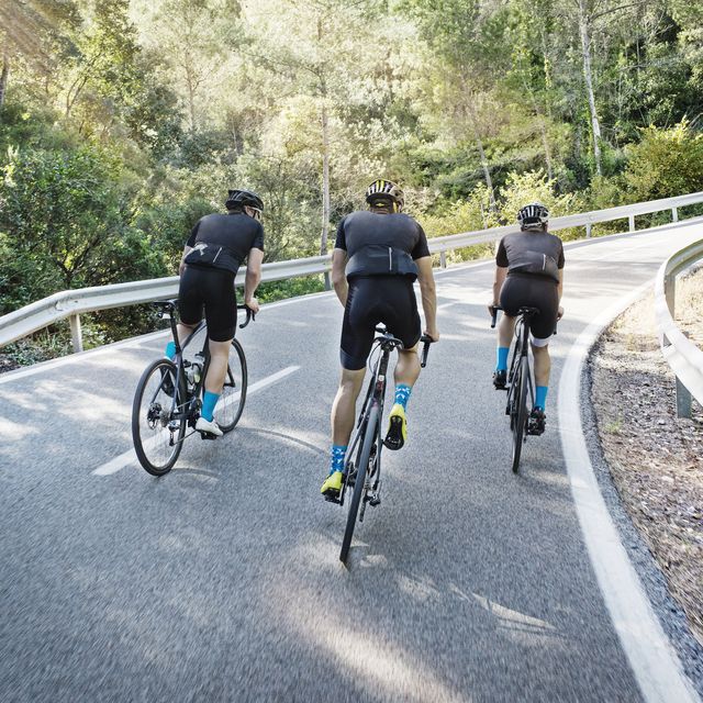 Rear view of male friends cycling on road