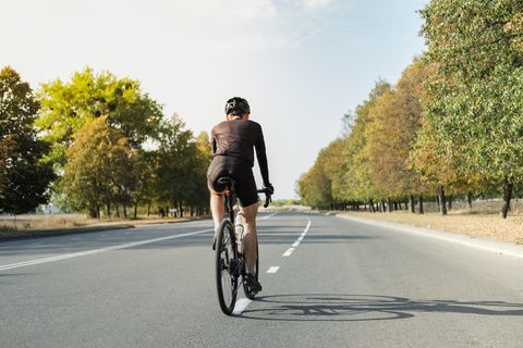 rear view of man riding bicycle on road