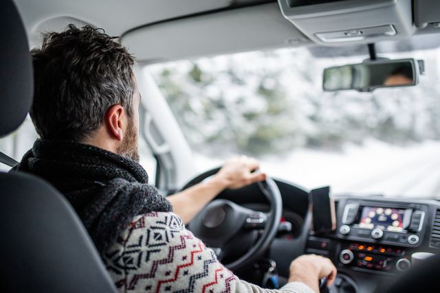 rear view of mature man driving car on snowy road
