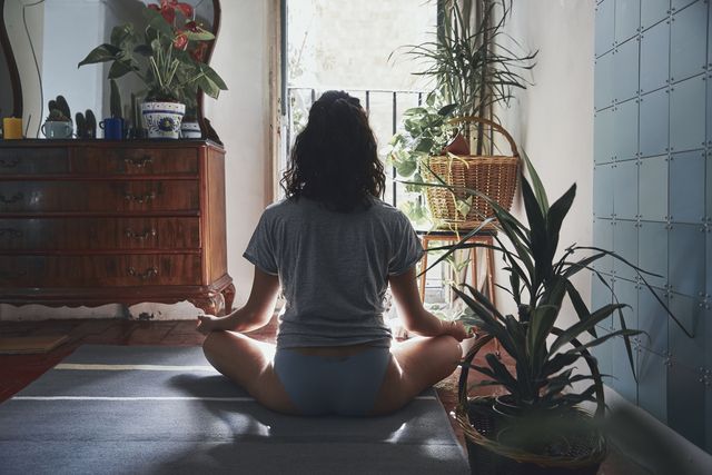 rear view of woman meditating while sitting at home